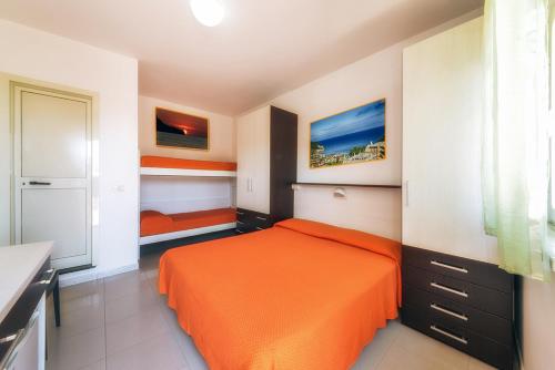 a bedroom with an orange bed and a kitchen at Hotel Incontro in Peschici