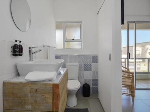 uma casa de banho com um lavatório, um WC e um espelho. em 19 Beach Road na Cidade do Cabo