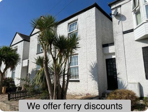 a white house with palm trees in front of it at Charming house by the sea in Ryde