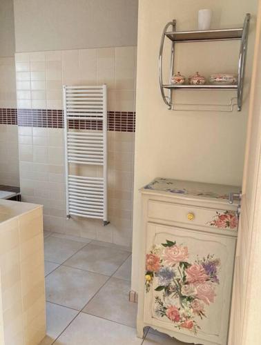 La salle de bains est pourvue d'un lavabo et d'une armoire ornée de fleurs. dans l'établissement Villa de charme avec piscine 5 min d'Avignon, aux Angles (Gard)