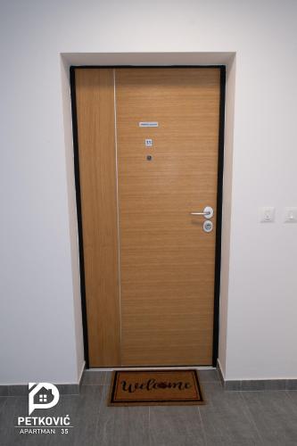 a wooden door in a room with a mat at Petković apartmani 35 in Jagodina