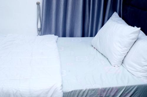a white bed with a pillow on top of it at Coded Hub Guest House in Lekki