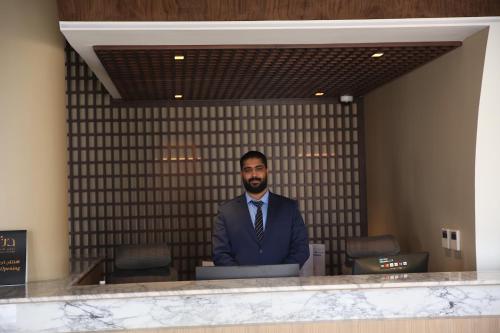 a man in a suit and tie standing behind a counter at أجنحة درة Dorra Suites in Riyadh