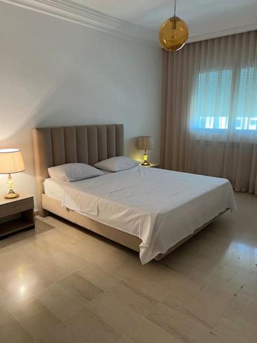1 dormitorio con 1 cama blanca grande y ventana en Luxury 2 bedrooms apartment jardin de carthage en Túnez