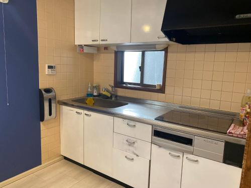 a kitchen with white cabinets and a sink and a window at Asakusa Inn 屋上バルコニー付き100m2広々快適一棟ハウス in Tokyo