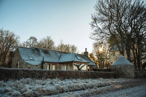 a house with snow on the ground next to a fence at Kinkell Cottage in Dingwall