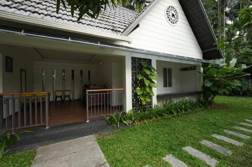 a front porch of a house with a yard at Royad Calicut Farm House - Premium Villa with Pool Inside a Farm in Kozhikode
