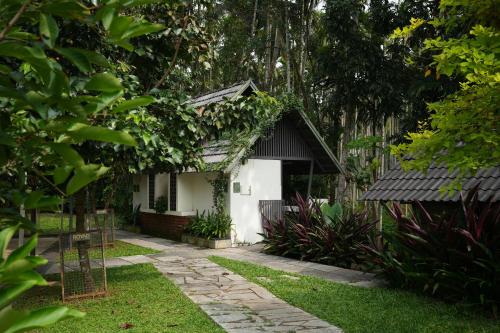 a small white house with a black roof at Royad Calicut Farm House - Premium Villa with Pool Inside a Farm in Kozhikode