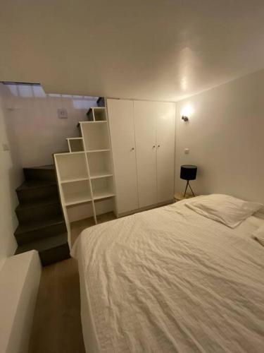 une chambre avec un lit et un escalier avec des armoires blanches dans l'établissement Le fameux Montmartre, à Paris