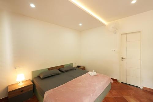a bedroom with a bed and a white wall at Royad Calicut Farm House - Premium Villa with Pool Inside a Farm in Kozhikode