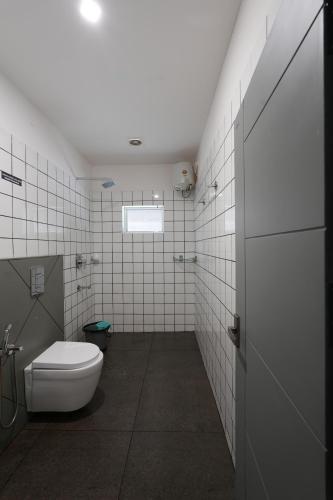 a bathroom with a white toilet and a window at Royad Calicut Farm House - Premium Villa with Pool Inside a Farm in Kozhikode