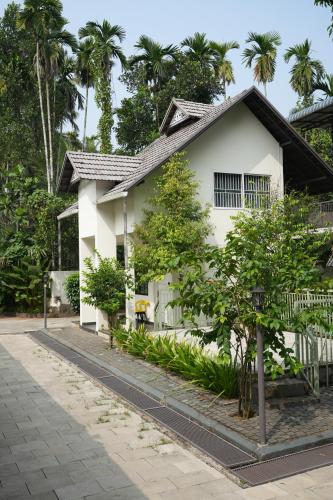 a white house with trees in front of it at Royad Calicut Farm House - Premium Villa with Pool Inside a Farm in Kozhikode