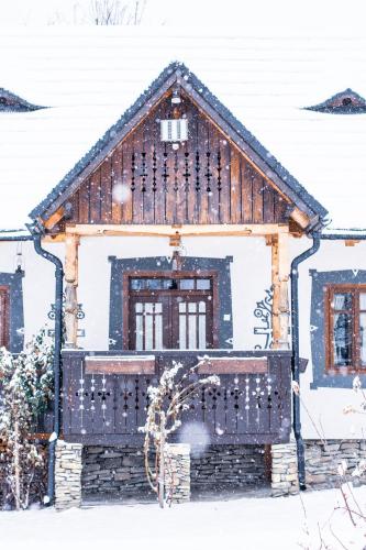 a house covered in snow with a fence at Pension La Roata in Gura Humorului