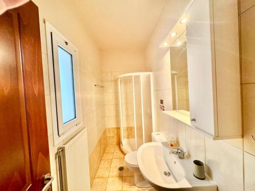 a bathroom with a sink and a toilet and a window at Giorgos Large Size Apartments -Family Friendly with Free Parking and Yard Views in Heraklio