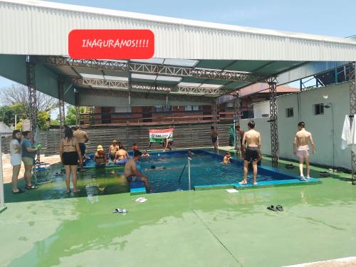 a group of people standing around a swimming pool at Bungalows Archi in Termas del Daymán