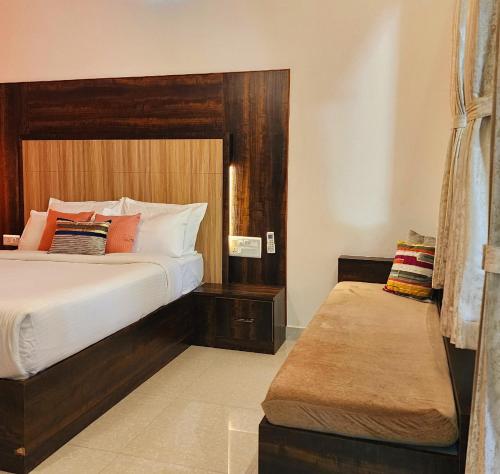 a bedroom with a large bed and a bench in it at Riyavar Luxury Homestay in Siddapur