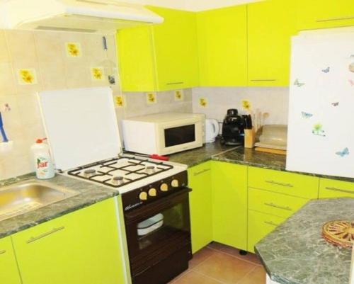 uma cozinha com armários amarelos e um forno com placa de fogão em Sziszi nyaralóház em Balatonszárszó