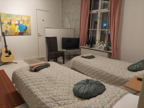 een slaapkamer met 2 bedden en een televisie en een gitaar bij Nostalginen residenssi Taika in Varkaus