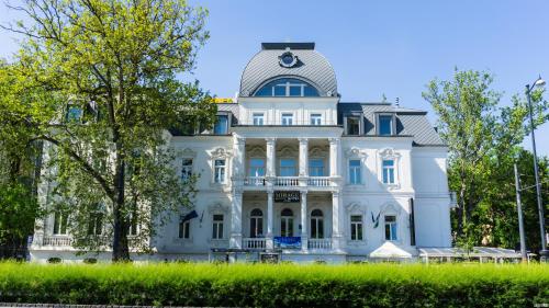 a large white house with a clock on it at Mirage Medic Hotel in Budapest