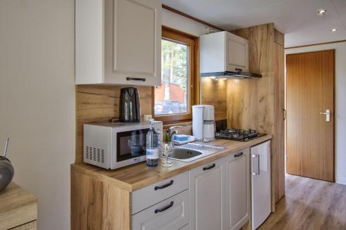 a kitchen with white cabinets and a microwave and a sink at Camping-und Ferienpark Havelberge in Groß Quassow