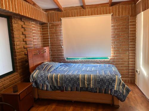 a bedroom with a bed and a brick wall at Linda Casa en Barrio Residencial la Herradura Oriente a 5 min playa in Coquimbo