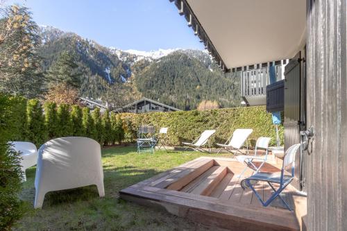 un patio avec des chaises et une terrasse avec des montagnes en arrière-plan. dans l'établissement Le Jardin de Champraz, à Chamonix-Mont-Blanc
