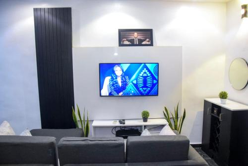 a living room with a couch and a tv on a wall at The Grenadines Apartment in Lagos