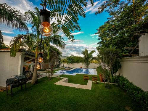 einen Hinterhof mit einem Pool und einer Palme in der Unterkunft Pousada Manacá Exclusive Suítes in Rifaina