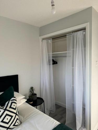um quarto com uma cama e uma janela com cortinas brancas em Apartment Close to the Studios em Borehamwood