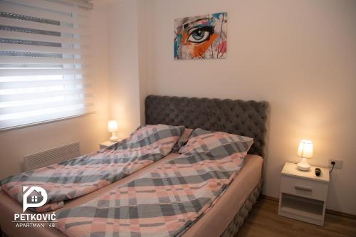 a bedroom with a bed with a plaid comforter at Petković apartmani 48 in Jagodina