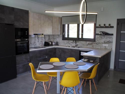 a kitchen with a table and yellow chairs at Nostos Luxury Villas with Private Pool in Nafpaktos in Nafpaktos