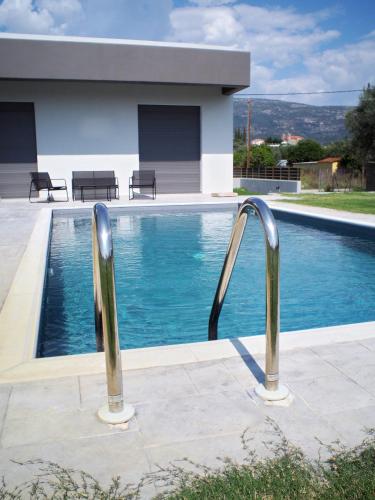 a swimming pool with two metal rails next to a house at Nostos Luxury Villas with Private Pool in Nafpaktos in Nafpaktos