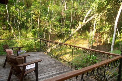 a wooden deck with chairs and a view of a forest at Pousada Terra Crua in Visconde De Maua