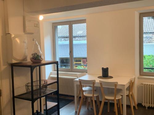 une cuisine avec une table, des chaises et des fenêtres dans l'établissement La Maison aux Volets Bleus 2ème Étage, à Vic-sur-Cère