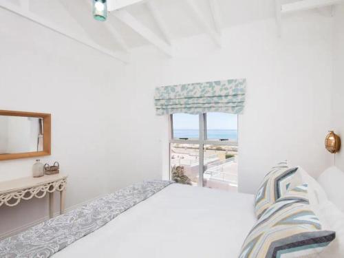 a white bedroom with a bed and a window at Summerseas in Summerstrand