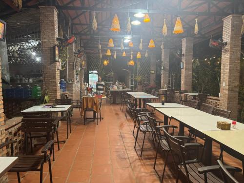 an empty restaurant with tables and chairs and lights at Bầu Bí Mini Farmstay Mekong - Tiền Giang in My Tho