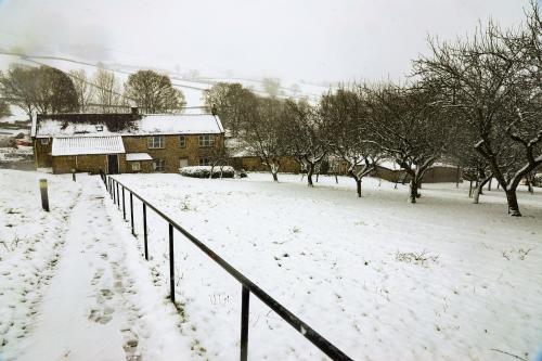 a snow covered field with a house and a fence at Cliff College in Curbar