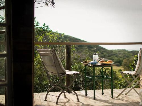 a table and chairs on a balcony with a view at Chelsea Manor in Kini Bay
