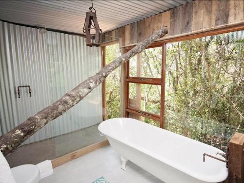 a bathroom with a bath tub and a tree branch at Chelsea Manor in Kini Bay