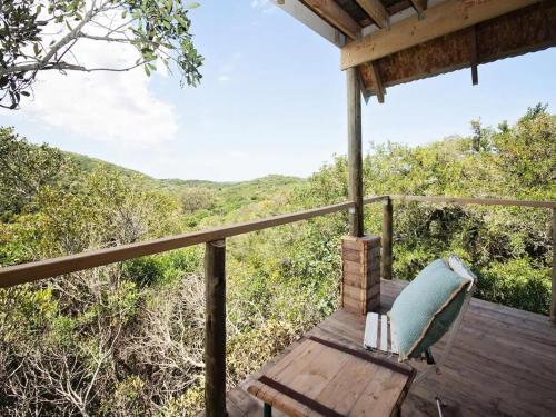 a bench on a deck with a view of the forest at Chelsea Manor in Kini Bay