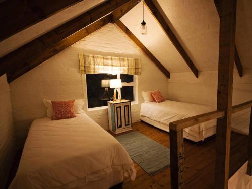 a attic room with two beds and a window at Chelsea Manor in Kini Bay