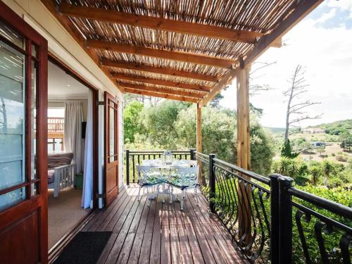 a wooden deck with a table on a balcony at Chelsea Manor in Kini Bay