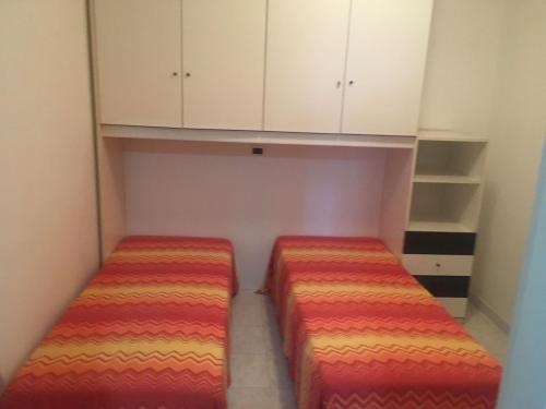 two beds in a small room with white cabinets at VILLAGGIO ANDORA COLOMBO in Marina dʼAndora