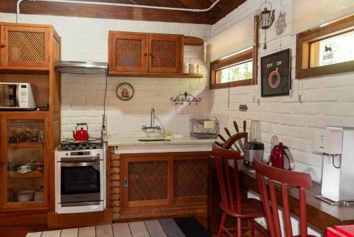 a kitchen with a stove and a counter with chairs at Pousada Terra Crua in Visconde De Maua