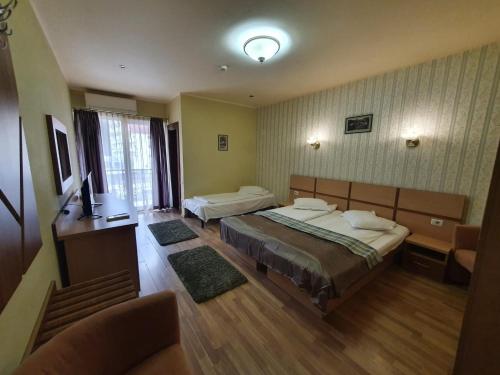 a hotel room with two beds and a television at Hotel Stogu in Băile Olăneşti