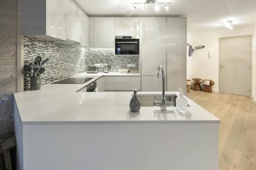 eine weiße Küche mit einer Spüle und einer Theke in der Unterkunft Taragan - Totally Refurbished 3 bed apt, Central St Gervais! in Saint-Gervais-les-Bains