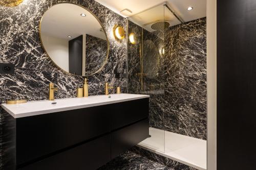 une salle de bain noire avec un lavabo et un miroir dans l'établissement DIFY Opera Diva - Hotel de Ville, à Lyon