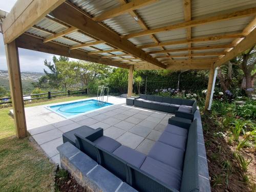 an outdoor patio with a pergola and a swimming pool at Manhattan Estates - Plettenberg Bay in Plettenberg Bay