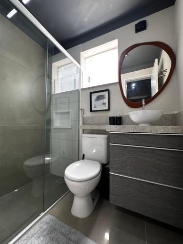 uma casa de banho com um WC, um lavatório e um espelho. em Casa Chicago em Aquiraz