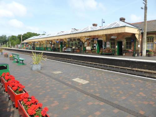 a train station with red flowers on the platform at 4 Marriotts Way in Sheringham